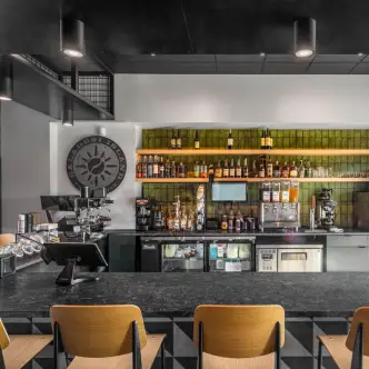 Modern bar interior with stools, espresso machine and bottle display